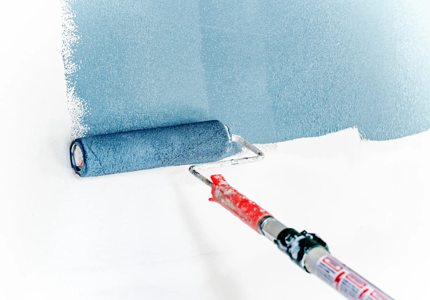 Rullo che stende una pittura azzurra su una parete